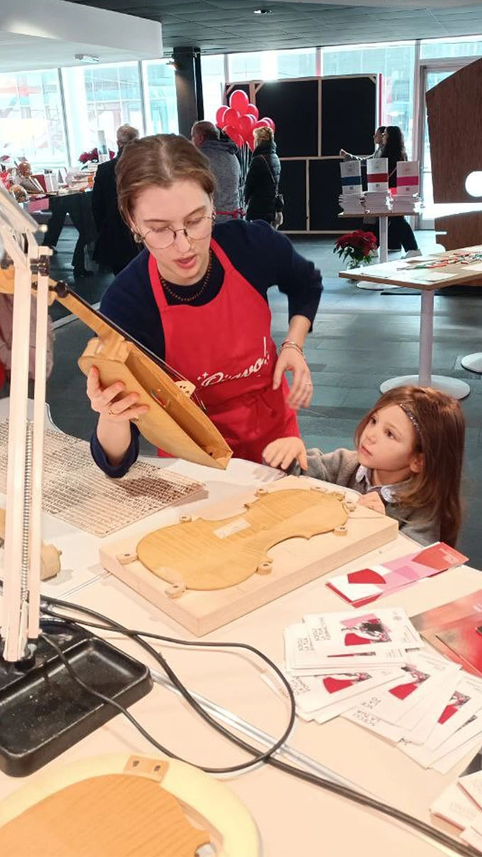 un maestro liutaio mostra ad una bambina l'antico mestiere